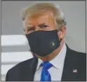  ?? (File photo/AP/Patrick Semansky) ?? President Donald Trump wears a face mask July 11 as he walks down a hall during a visit to Walter Reed National Military Medical Center in Bethesda, Md. When Trump wore a mask publicly for the first time on Saturday, he chose a navy-blue one that bore the presidenti­al seal. It also matched the color of his suit.