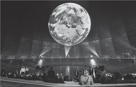  ?? MARTIN MEISSNER / ASSOCIATED PRESS ?? Visitors watch an art installati­on of earth at an exhibition in Oberhausen, Germany, on Thursday.