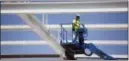 ?? ANNIE RICE — THE ASSOCIATED PRESS ?? A constructi­on worker lowers himself on a forklift at a constructi­on site in Chicago. Spending on U.S. constructi­on projects ticked up 0.1 percent in July.