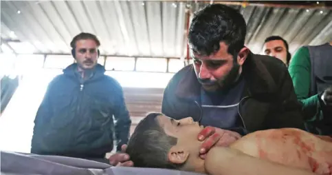  ?? — AFP ?? DOUMA, Syria: A father mourns over the body of his 11-year-old son Ahmad, who was killed along with a friend when a cluster bomb exploded in his backyard, at a makeshift morgue in this rebel-held town on the eastern outskirts of the capital Damascus...