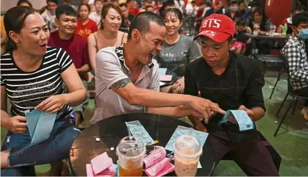  ?? — aFP ?? Colour of money: Patrons playing lotto conducted by the ‘Sai Gon Tan Thoi’ troupe in Binh duong province while another performer (below) gets ready for her act in Ho Chi Minh City.