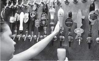  ?? PHIL COALE/AP ?? Brittany Callens, a bartender at the Leon Pub, draws a beer from one of the many taps at the bar in Tallahasse­e in 2009. Legislator­s are considerin­g a measure that would allow restaurant­s to include alcoholic drinks with take-out orders.
