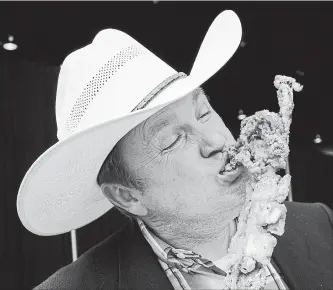  ?? JEFF MCINTOSH THE CANADIAN PRESS ?? James Radke, midway operations manager at the Calgary Stampede, samples a deep fried giant squid that will be available at this year's Stampede in Calgary.