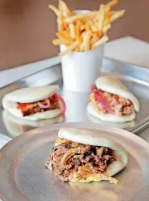  ?? [PHOTOS BY JIM BECKEL, THE OKLAHOMAN] ?? This is a selection of steamed buns with an order of fries from Ur/Bun in Oklahoma City’s Uptown.