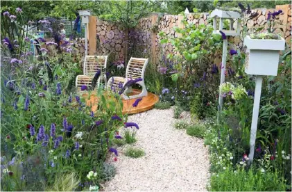  ??  ?? A curved gravel path leads to a circular deck in this small show garden, where a screen of buddleia and other pollinator­friendly plants provide privacy