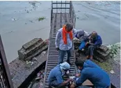  ?? — AFP ?? Railway employees check the raised water levels in Yamuna after heavy rains in New Delhi on Friday.