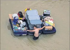  ?? REUTERS ?? Residents wade through flood waters with their belongings in Houston on Wednesday.