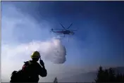  ?? NOAH BERGER — THE ASSOCIATED PRESS FILE ?? In this file photo a helicopter drops water while battling the Kincade Fire near Healdsburg As wildfire risks heat up, startups in California’s Silicon Valley are starting to take notice. One startup makes a fire retardant spray that is safe for plants and designed to keep fires from spreading.