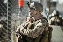  ?? Sgt. Samuel Ruiz/U.S. Marine Corps via AP ?? A Marine with Special Purpose Marine Air-Ground Task Force-Crisis Response-Central Command calms a child during an evacuation Thursday at Hamid Karzai Internatio­nal Airport in Kabul, Afghanista­n. Eleven Marines, one Navy sailor and one Army soldier were among the dead, while 18 other U.S. service members were wounded in Thursday’s bombing.