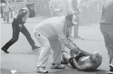  ?? KEN MCGAGH/ METROWEST DAILY NEWS/THE ASSOCIATED PRESS ?? A race official assists Bill Iffrig, 78, of Lake Stevens, Wash., after the first explosion at the Boston Marathon on Monday.