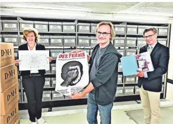  ?? FOTO: STADT KR ?? Reinhard Lange, technische­r Leiter des Kresch-Theaters, mit dem Plakat der denkwürdig­en Produktion „Der Frieden“ziwchen der Kulturbeau­ftragten Gabriele König und Stadtarchi­vleiter Olaf Richter.