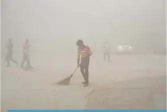  ??  ?? NEW DELHI: Indian workers use brooms to sweep away dust in the morning fog in Greater Noida, near New Delhi. A thick gray haze has enveloped India’s capital region as air pollution hit hazardous levels.