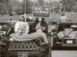  ?? Rachel Mummey / Bloomberg ?? Attendees hold signs during a drive-in rally for Democratic presidenti­al candidate Joe Biden at the Iowa State Fairground­s in Des Moines.