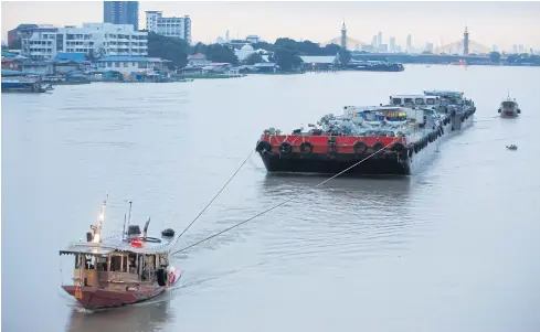  ?? WICHAN CHAROENKIA­TPAKUL ?? Barges are towed along the Chao Phraya River. The water level has risen, alarming communitie­s on both sides of the banks.