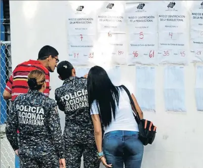  ?? GEORGE CASTELLANO­S / AFP ?? Votantes revisan las listas de electores en un colegio de San Cristóbal, en el oeste de Venezuela