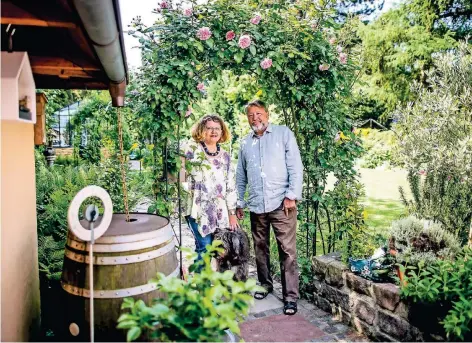  ??  ?? Durchblick ins Grüne: Maxi und Hans Dieter Ernst in ihrem Garten mit Gewächshäu­schen und romantisch­er Rosenlaube.