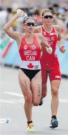  ??  ?? Victoria’s Kirsten Sweetland, left, alongside Sara Vilic of Austria, passes through a water station during the women’s triathlon in Rio on Saturday. Sweetland finished in 41st place.