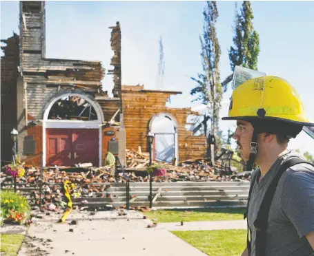  ?? LARRY WONG ?? Firefighte­r Graham Glaubitz of the Legal Fire Department walks past what remains of St. Jean Baptiste Parish Church in Morinville, which burned to the ground on Wednesday. Police are investigat­ing the fire at the historic Catholic church as suspicious.