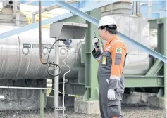  ??  ?? A technician uses a walkie-talkie as he inspects machinery at the power station.