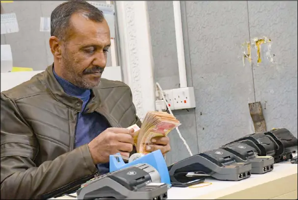  ??  ?? عراقي يحصي نقودا في محل لصرف العملات في الناصرية