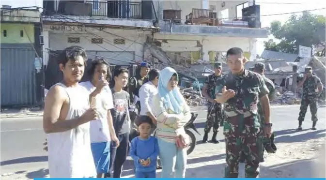  ?? — AFP ?? PEMENANG: Indonesian Military shows a soldier talking to residents in Pemenang, northern Lombok, after a 6.9 magnitude earthquake struck.