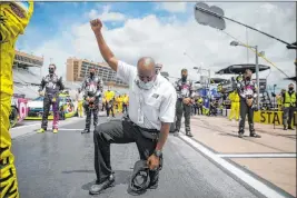  ?? Brynn Anderson The Associated Press ?? A NASCAR official kneels in protest of social injustice in America during the national anthem before Sunday’s Cup race at Atlanta Motor Speedway in Hampton, Ga.