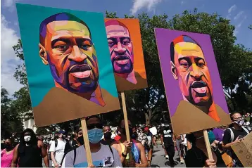  ?? AP Photo/Carolyn Kaster, File ?? ■ In this Aug. 28, 2020, file photo, people carry posters with George Floyd on them as they march from the Lincoln Memorial to the Martin Luther King Jr. Memorial in Washington. As the anniversar­y of George Floyd’s murder approaches, some people say the best way to honor him is for Congress to pass a bill in his name that overhauls policing.