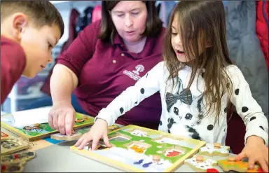  ?? NWA Democrat-Gazette/CHARLIE KAIJO ?? Pre-K teacher Laura Thompson (center) works on a puzzle with Knox Hensley-Nichols, 5, (from left) and Audrina Williamson, 5, at Helen R. Walton Children’s Enrichment Center in Bentonvill­e.