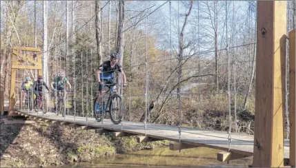  ?? Jodi Tonsic ?? Bicyclists cross a suspension bridge while enjoying some of the many trails in the Yadkin Valley.