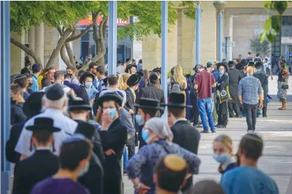  ?? (Olivier Fitoussi/Flash90) ?? PEOPLE WAIT at a temporary vaccine center outside City Hall in Jerusalem for their third dose of the COVID-19 vaccine.