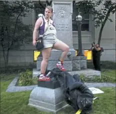  ?? Jonathan Drew/Associated Press ?? Claire Meddock, 21, stands on a toppled Confederat­e statue Monday evening in Durham, N.C. Activists used a rope to pull down the monument outside the courthouse.