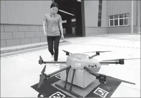  ?? XINHUA ?? An employee of Cainiao Network, the logistics arm of Alibaba, receives a delivery from a drone at a storage facility in Xi’an, capital of Shaanxi province.