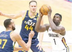  ??  ?? Zion Williamson of the New Orleans Pelicans looks to shoot against Rudy Gobert (27) and Bojan Bogdanovic of the Utah Jazz. (AFP)