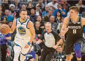  ?? REUTERS PIC ?? Warriors’ Stephen Curry (left) with the ball against Kings’ Bogdan Bogdanovic in their game in Sacramento on Friday.