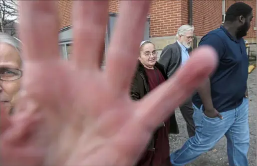  ?? Stephanie Strasburg/Post-Gazette ?? Maryann Fisher, left, of Alexandria, blocks a photograph­er’s camera as her husband, former pastor David Fisher, second from right, leaves the Huntingdon County Courthouse Jan. 10 after pleading no contest to a felony charge of endangerin­g the welfare of a child by failing to report sexual abuse.