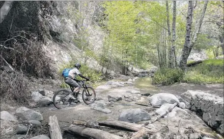  ?? Silvia Razgova For The Times ?? MIKE McGUIRE, a volunteer with the Angeles Forest Mountain Bike Patrol, crosses the Arroyo Seco after supervisin­g others who had worked on restoring a stretch of the Gabrielino Trail in the San Gabriel Mountains. It has been closed since the 2009...