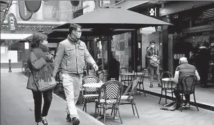  ?? -REUTERS ?? People walk past a cafe after the coronaviru­s disease (COVID-19) restrictio­ns were eased for the state of Victoria, in Melbourne, Australia.