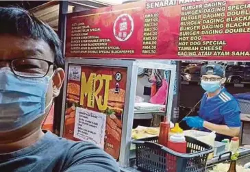  ?? BERNAMA PIC ?? A customer taking a selfie with Shazrin Hafeez Fadzlan (right) at his burger stall in Taman Johor Jaya, Johor Baru.