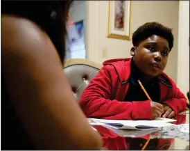  ?? (Ap/steven Senne) ?? Evena Joseph (left) sits with her son J. Ryan Mathurin, 10, as he does his homework Dec. 22 at their home in Boston.