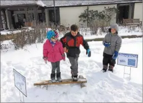  ?? CHAD FELTON — THE NEWS-HERALD ?? Five-year-old Kendall, left, and her brother, 9-year-old Caden, conquer the balance beam during Fun Day Monday on Jan. 15 at Penitentia­ry Glen Reservatio­n in Kirtland. Junior volunteer Eddie stands to the right.