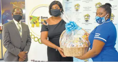  ?? CONTRIBUTE­D ?? Wife of the prime minister and founder of the Save Our Boys and Girls Foundation Juliet Holness (centre) presents a care package to third-year midwifery student at the University of Technology (UTech) Ashleigh Mitchell. Looking on is Acting President of UTech Professor Colin Gyles. The occasion was the presentati­on of care packages to 53 midwifery students at UTech’s Old Hope Road campus on Tuesday. The packages were donated through the Save Our Boys and Girls Foundation as part of its coronaviru­s (COVID-19) relief efforts.