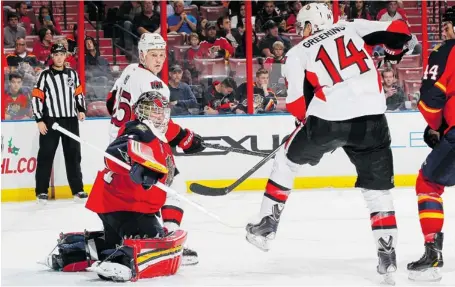  ?? JOEL AUERBACH/GETTY IMAGES ?? Chris Neil looks back as the puck deflects off of Senators teammate Colin Greening and over Florida Panthers goaltender Tim Thomas for what would be the game-winning goal Tuesday in Sunrise, Fla. Senators goalie Craig Anderson improved his career...