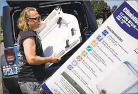  ?? Kori Suzuki Seattle Times ?? BRIAN GADZUK, 56, clears out the trunk of his Jeep to make space for a new air-conditioni­ng unit in the parking lot of McLendon Hardware in Renton, Wash.