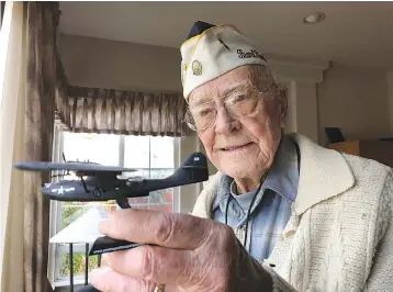  ?? AP Photo/Eric Risberg ?? ■ Retired U.S. Navy Commander Don Long holds up a replica of the military seaplane he was standing watch on when Japanese warplanes attacked Hawaii 77 years ago Friday at his home in Napa, Calif.