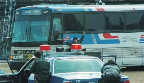  ?? WAYNE CUDDINGTON ?? RCMP officers keep watch on the hijacked bus on Parliament Hill as a two-way radio is being handed to the driver on April 7, 1989.
