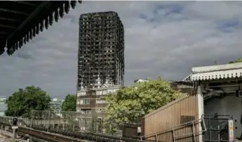  ?? ANDREW TESTA PHOTOS/THE NEW YORK TIMES ?? Grenfell Tower, now a blackened husk after last month’s fire, is visible from a nearby train platform in London.