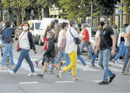  ??  ?? Decenas de personas, con mascarilla, cruzan un paso de cebra en una calle de Pamplona.