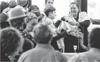  ?? PHOTOS BY CHERYL EVANS/THE REPUBLIC ?? Rabbi Tracee Rosen holds a loaf of challah, a braided bread traditiona­lly eaten as part of Jewish ceremonies, at the close of services at Temple Gan Elohim in Phoenix.