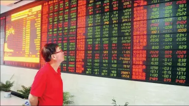  ?? WANG BIAO / FOR CHINA DAILY ?? An investor looks at share prices at a brokerage in Fuyang, Anhui province, on Friday.