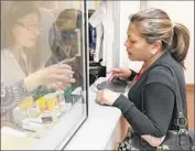  ?? Allen J. Schaben Los Angeles Times ?? LUCIA JIMENEZ has a prescripti­on filled by pharmacist Alaria Kiraz, left, at an AltaMed clinic in East L.A. The network serves low-income patients.